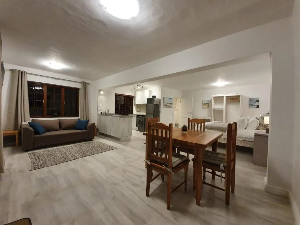Open-plan lounge, dining table and kitchenette leading to a sleeper couch nook