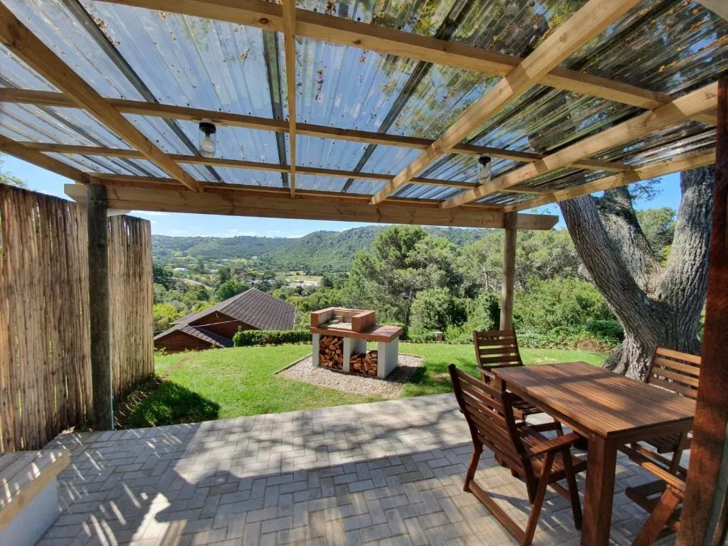 Covered patio with dining table, a built-in braai and a view over the valley to distant mountains