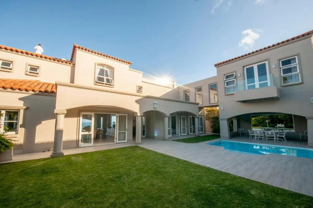 Villa courtyard with pool, lawn and arched covered walkways between wings