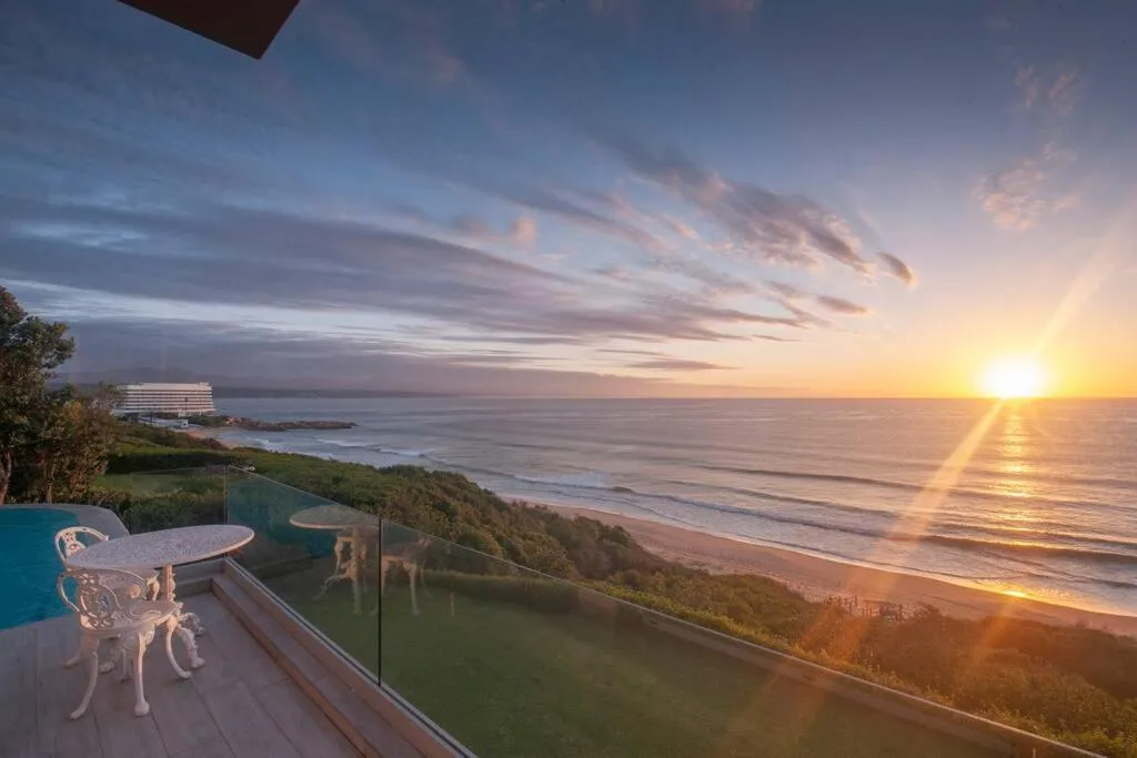 Terrace at sunset overlooking the pool edge, beach and ocean horizon