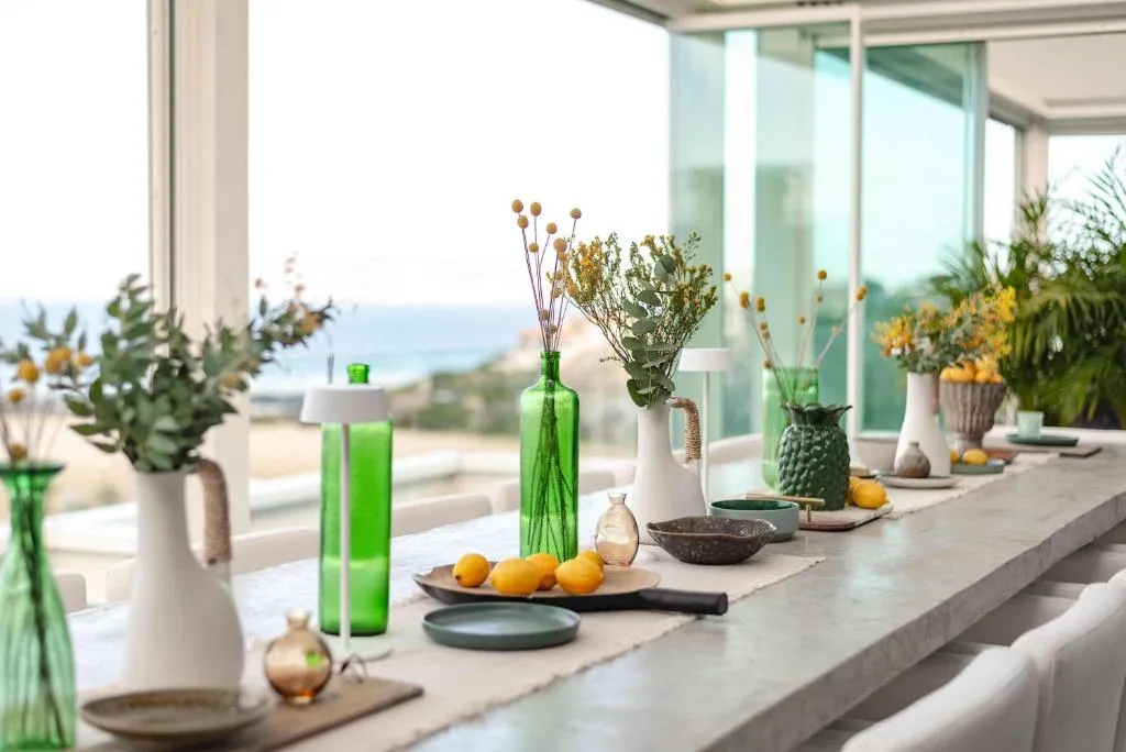 Long dining table styled with glass vases, dried flowers and a bowl of lemons