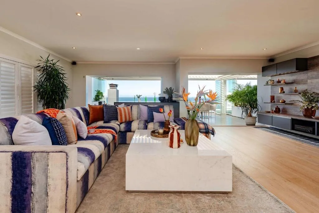 Living room with a striped sectional sofa and glimpses of the sea through sliding doors