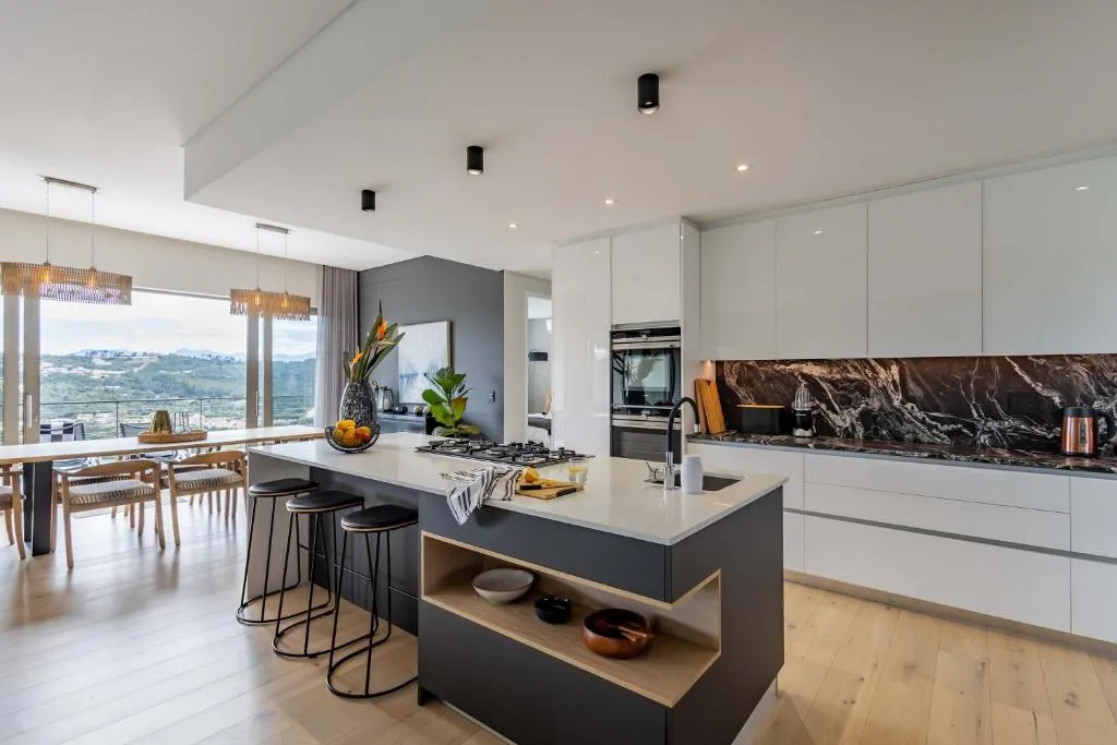 Kitchen with a dark island, marble splashback and a window framing the valley view