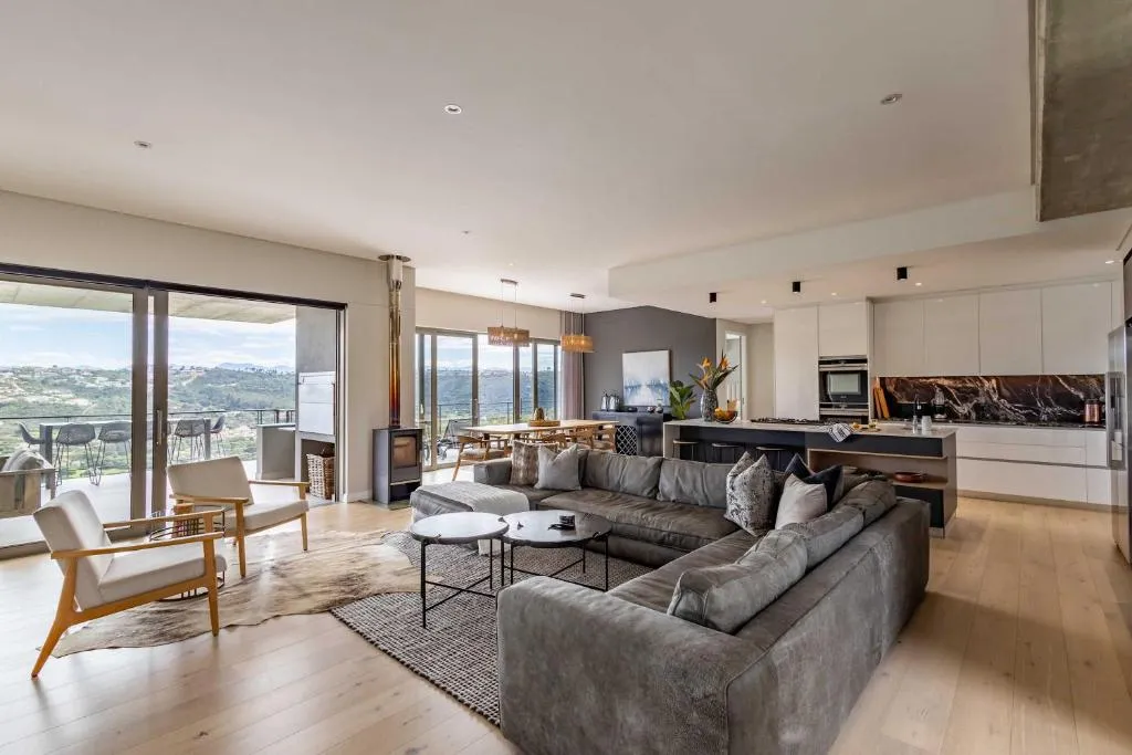 Open-plan living area with a wood burner and glass doors opening onto a balcony over the valley