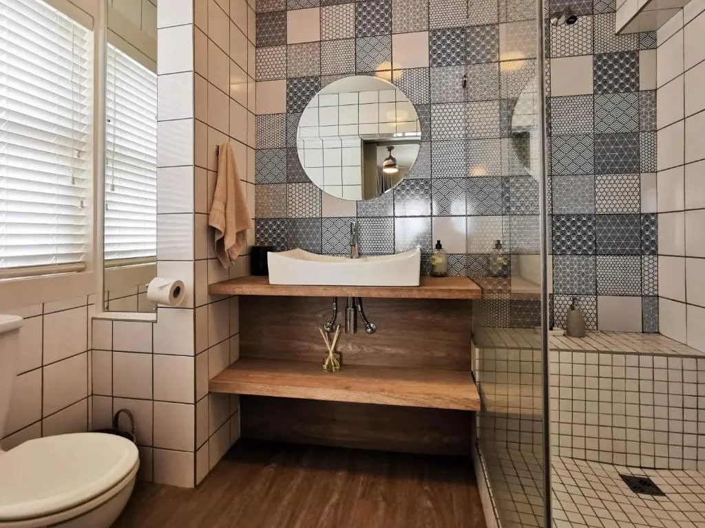 En-suite bathroom with patchwork mosaic tile, a timber-shelf vessel sink and a walk-in shower