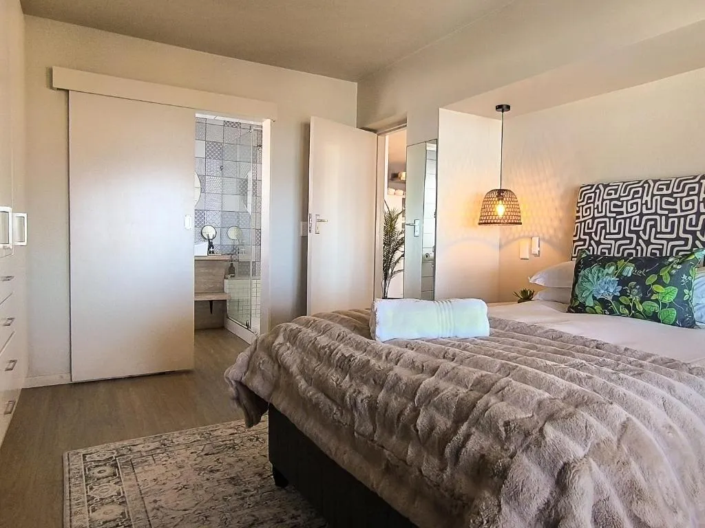 Bedroom with a faux-fur throw, geometric patterned headboard and an open door to the en-suite