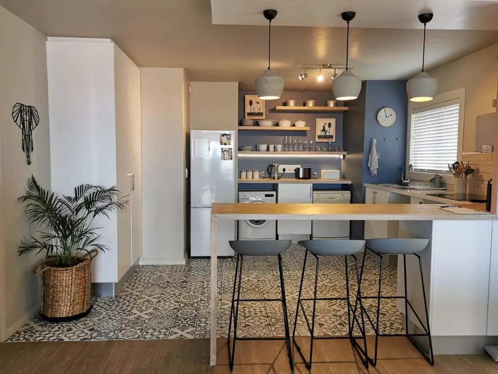 Open kitchen with white cabinetry, a navy accent wall, pendant lighting and a breakfast bar