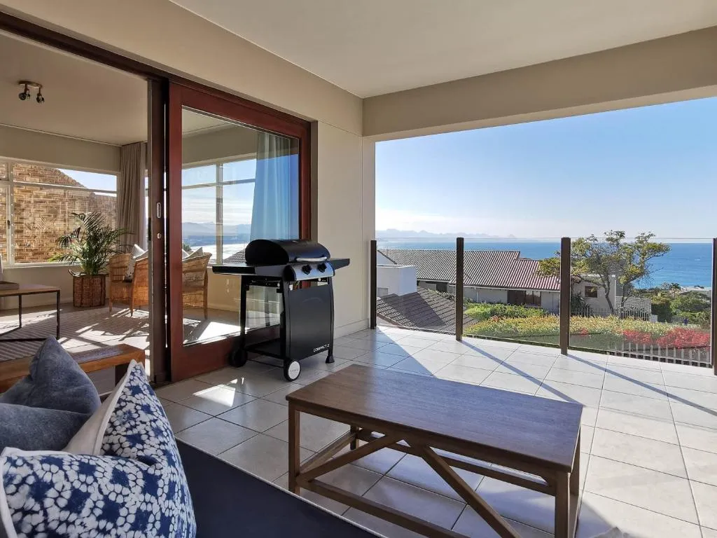 Tiled terrace with a gas braai and a glass balustrade overlooking rooftops to the sea