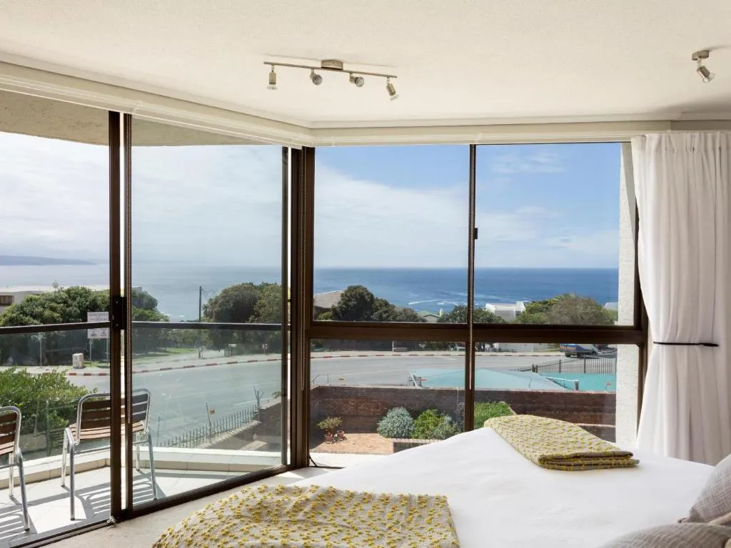 Bedroom window view over a shared pool and tennis court down to the sea