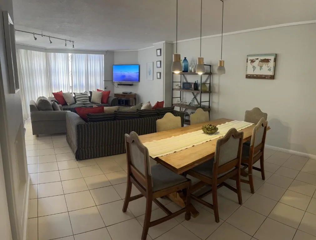 Dining table and grey corner sofa in an open-plan lounge with wall-mounted TV