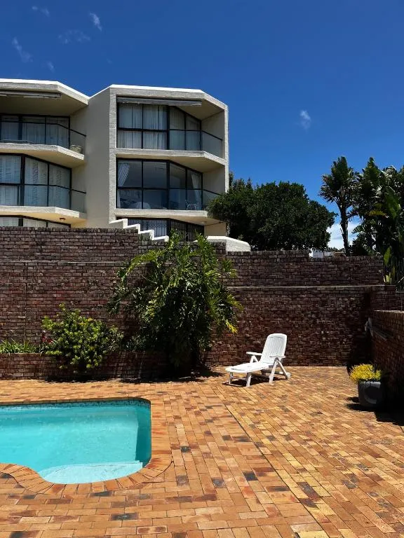 Apartment block exterior with a small brick-walled plunge pool and sun lounger