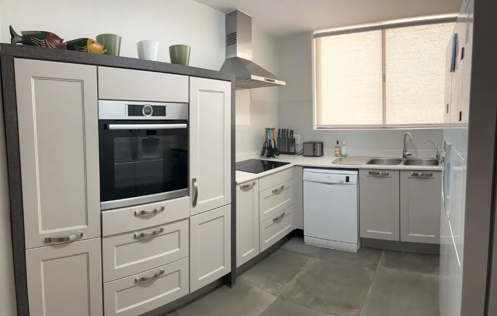 Galley kitchen with built-in oven, gas hob, extractor hood and dishwasher