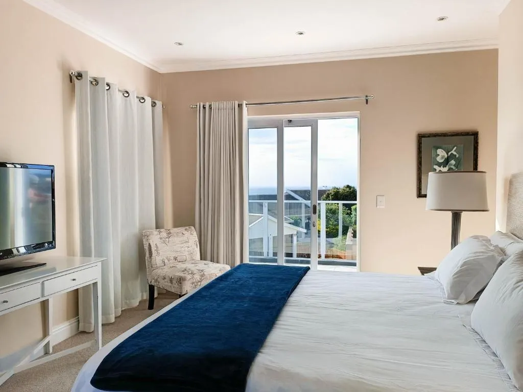 Bedroom with sliding doors onto a private balcony with a glimpse of the sea beyond rooftops