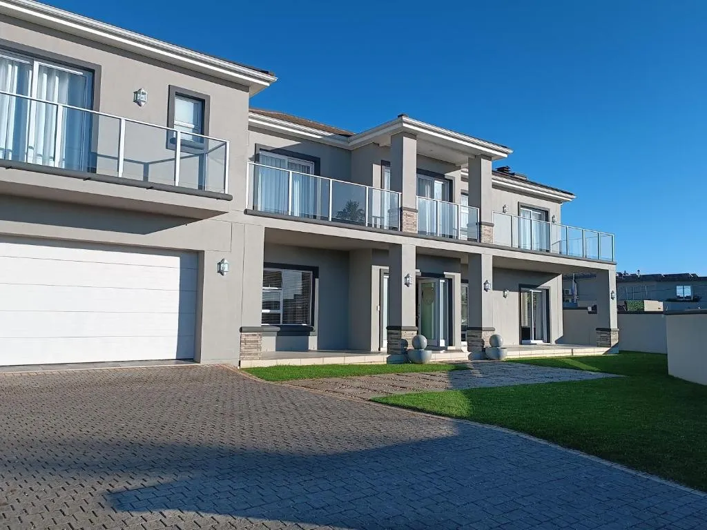 Grand double-storey house exterior with glass-balustrade balconies, a double garage and paved driveway