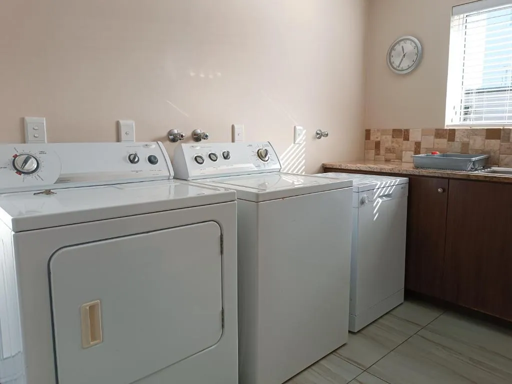 Laundry room with two washing machines, a tumble dryer and a tiled counter