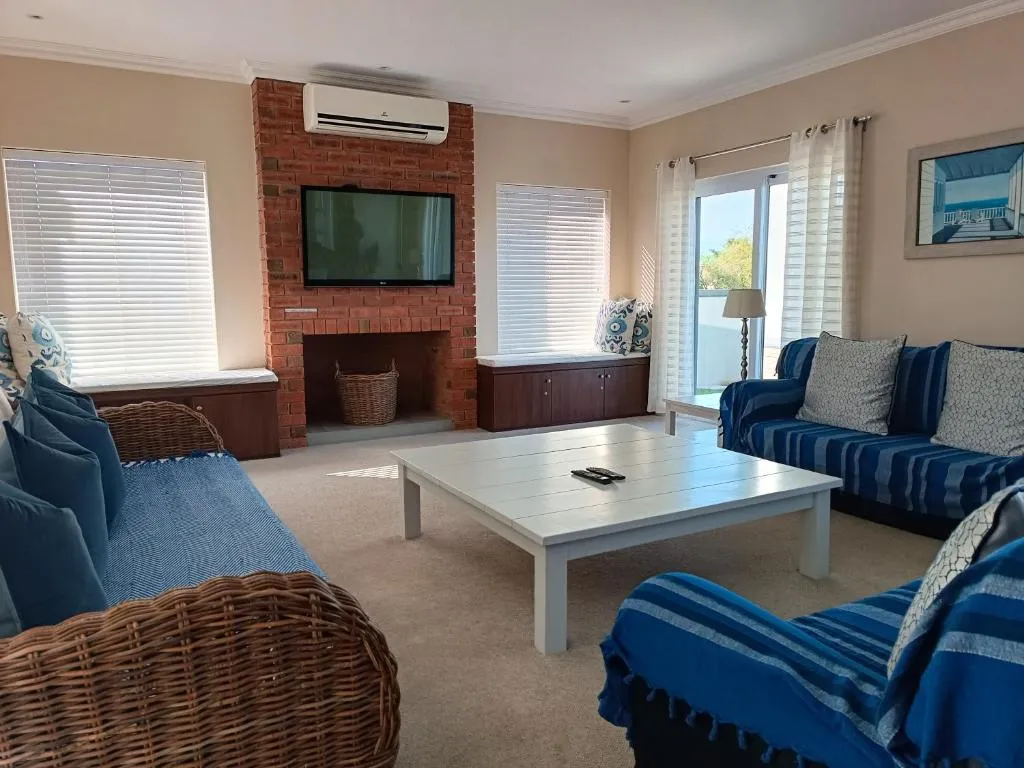 Living room with a brick fireplace, wall-mounted air conditioner and striped blue sofas
