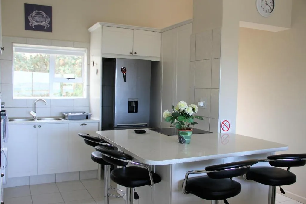 Kitchen island with induction hob, black bar stools and integrated fridge-freezer