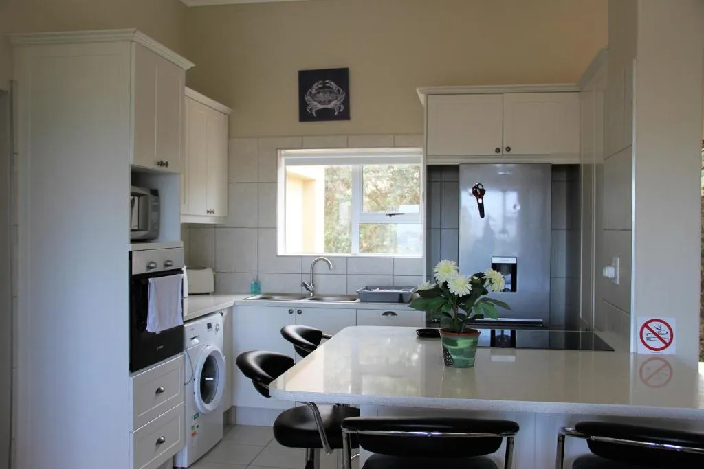 White kitchen with a washing machine and oven built in beside an island counter