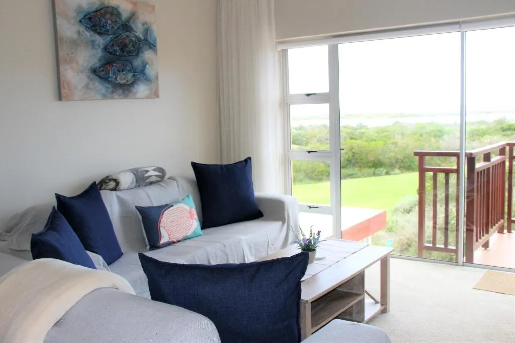 Lounge corner with navy cushions and sliding doors onto a wooden balcony over green lawn