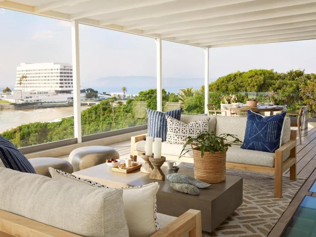 Covered terrace lounge with sofas facing the ocean and the coastline below