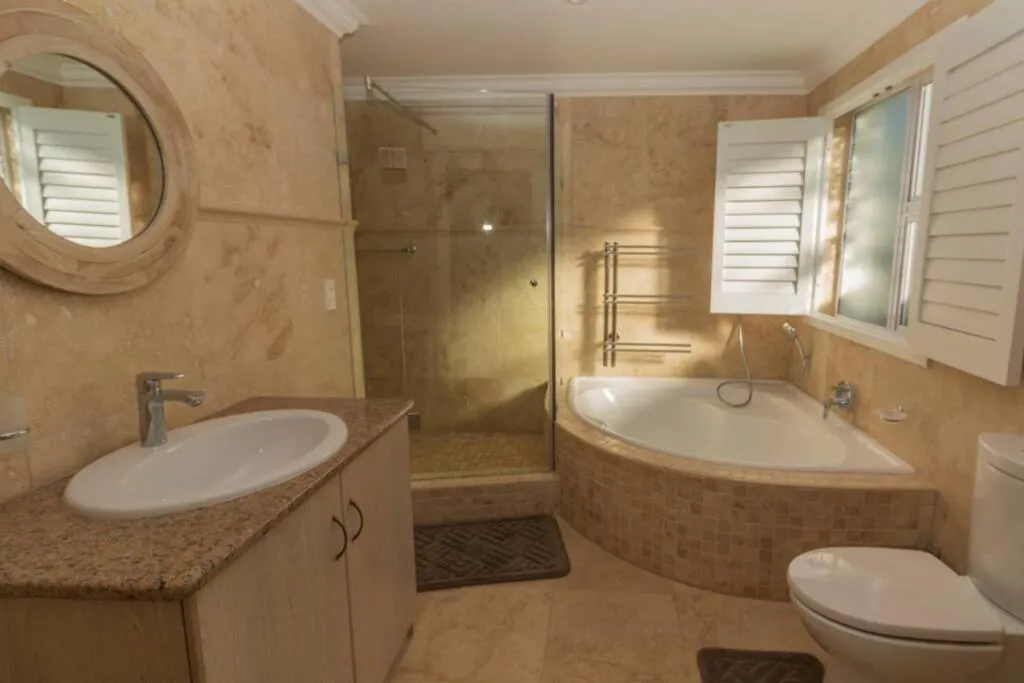 En-suite bathroom with a corner bath, glass shower and marble-tiled counter