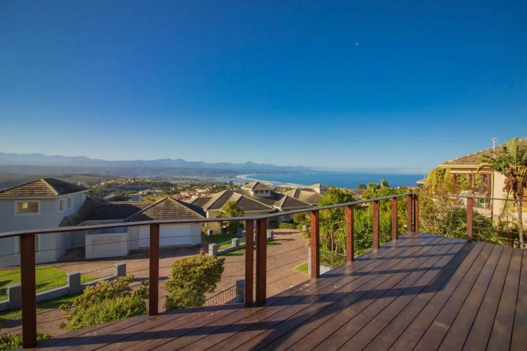 Wooden deck overlooking neighbourhood rooftops down to the Plettenberg Bay coastline and sea