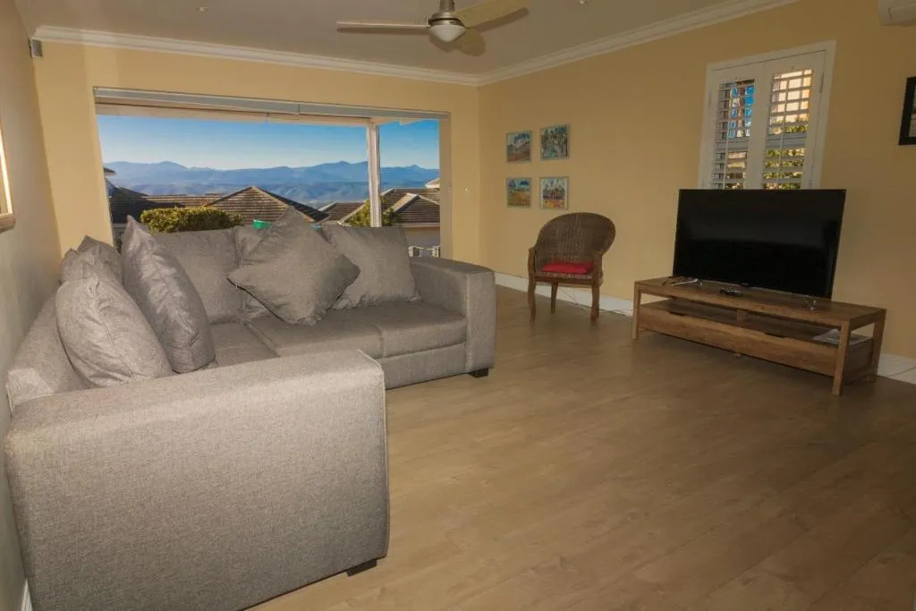Living room lounge with grey sofas, ceiling fan and a mountain view through the window
