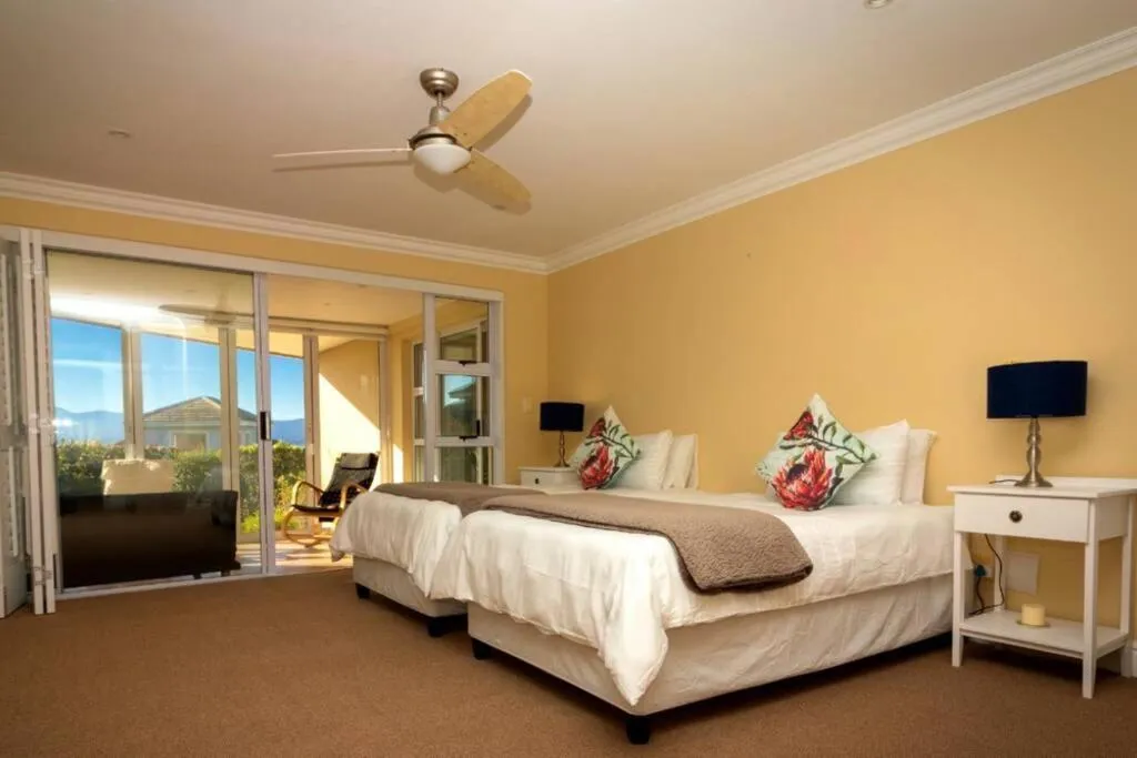 Twin bedroom in yellow tones with sliding doors opening onto a private balcony with mountain views