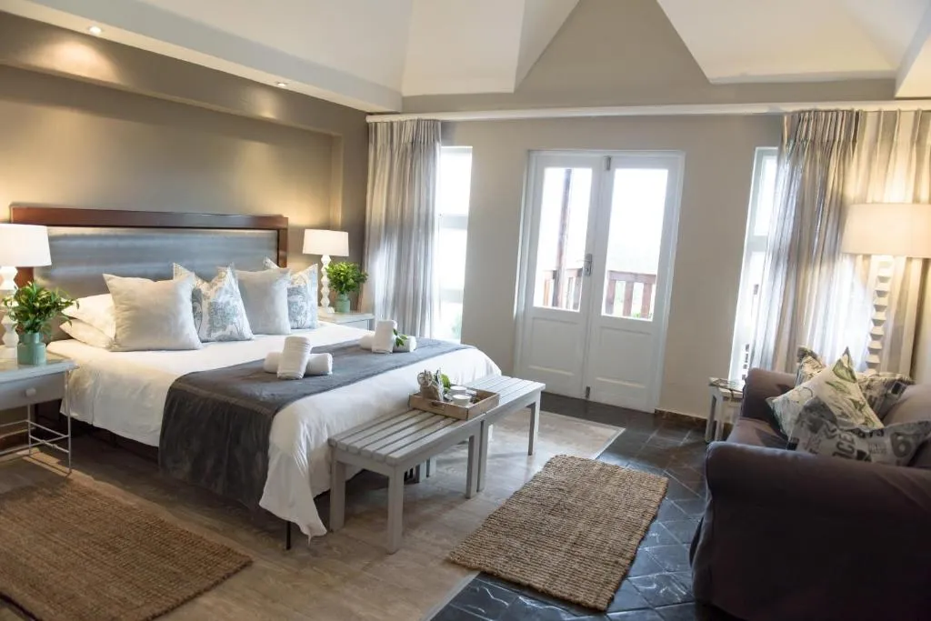 Hotel bedroom with a vaulted ceiling, a dark leather headboard and doors onto a private balcony