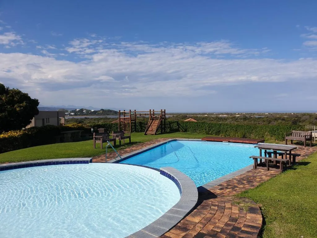 Shared swimming pool with sun loungers, a picnic table and a children's play structure