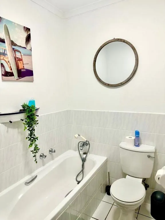 Bathroom with a round wood-framed mirror, freestanding bath, and a surfboard-themed canvas print