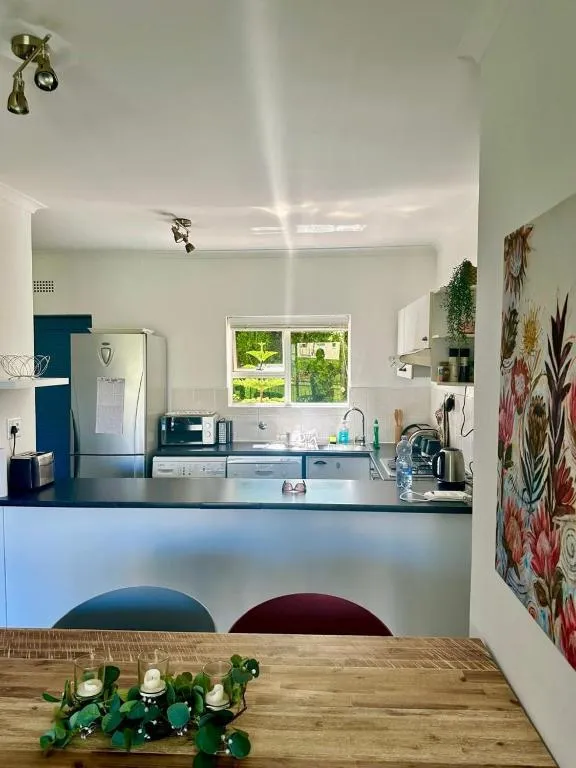 Galley kitchen with a fridge-freezer, microwave, and a window looking onto a garden courtyard