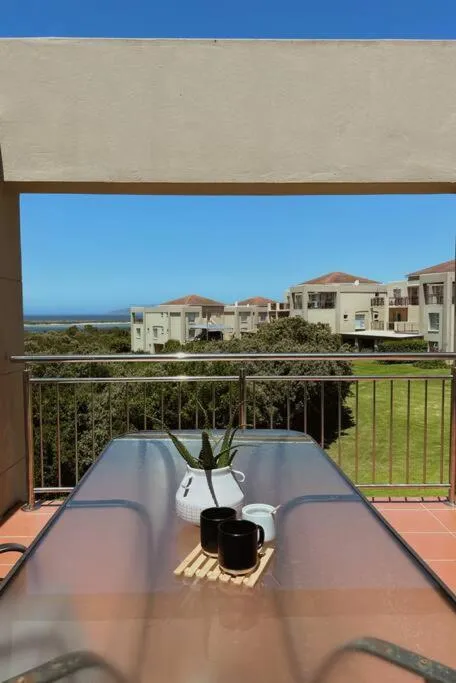 Balcony table set for coffee overlooking estate rooftops and lawns towards the coast