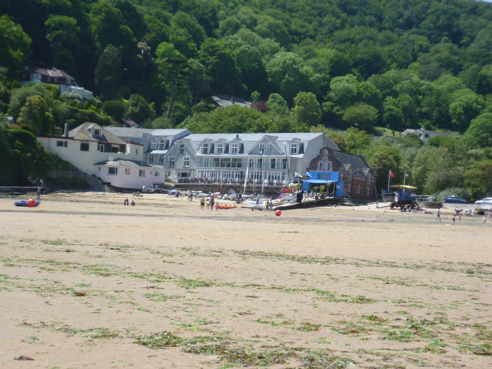 South Sands beach at Salcombe at low tide, with the beachfront hotel buildings behind the sand and a wooded hillside above them
