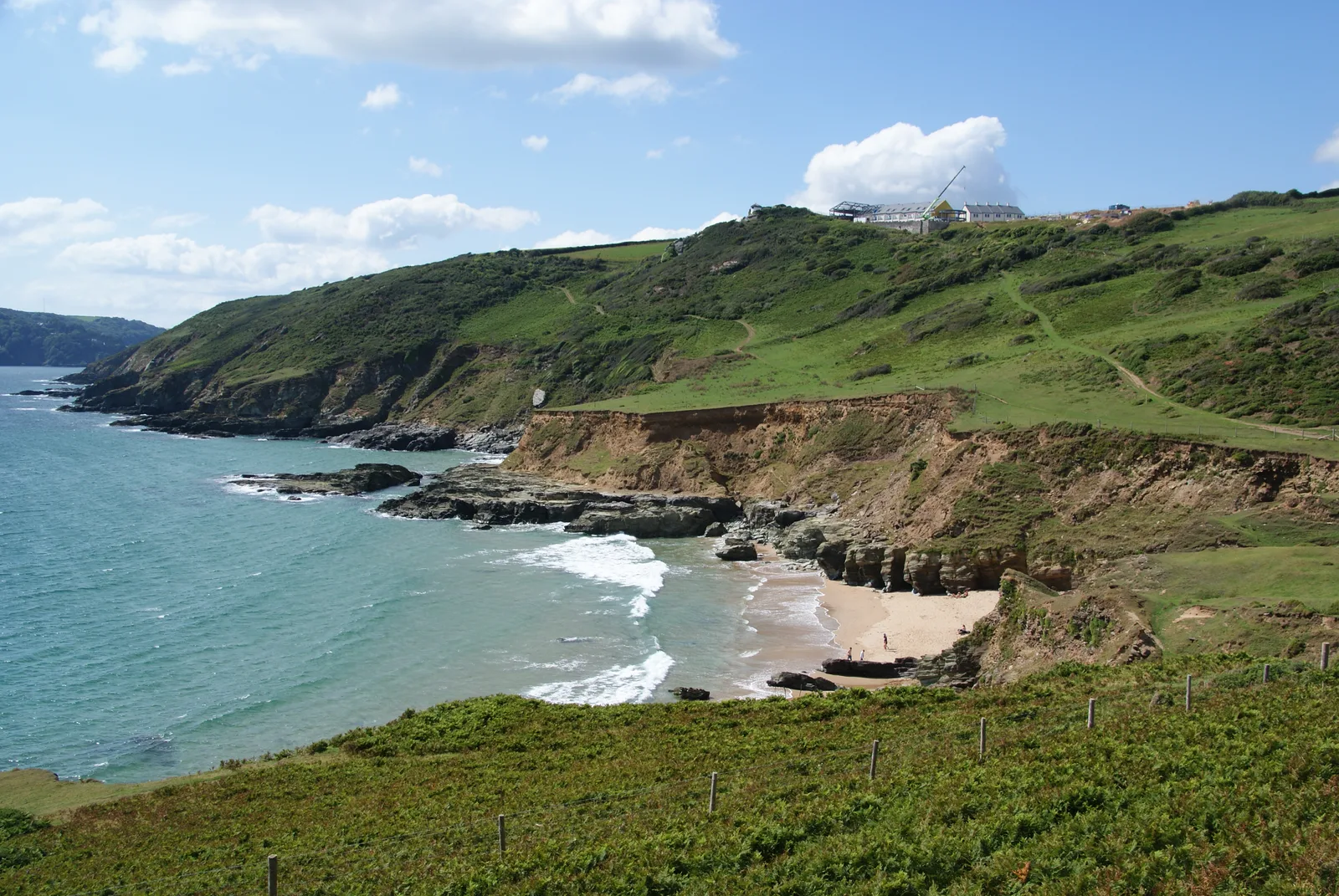 Gara Rock beach and the cliffs of the East Portlemouth shore, with buildings on the headland above the cove