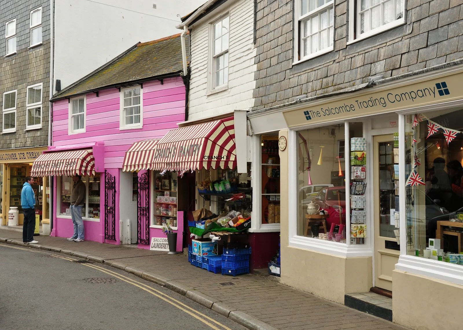 Shops along Fore Street in Salcombe, a narrow street of white and pastel-painted buildings with awnings and shopfronts on both sides