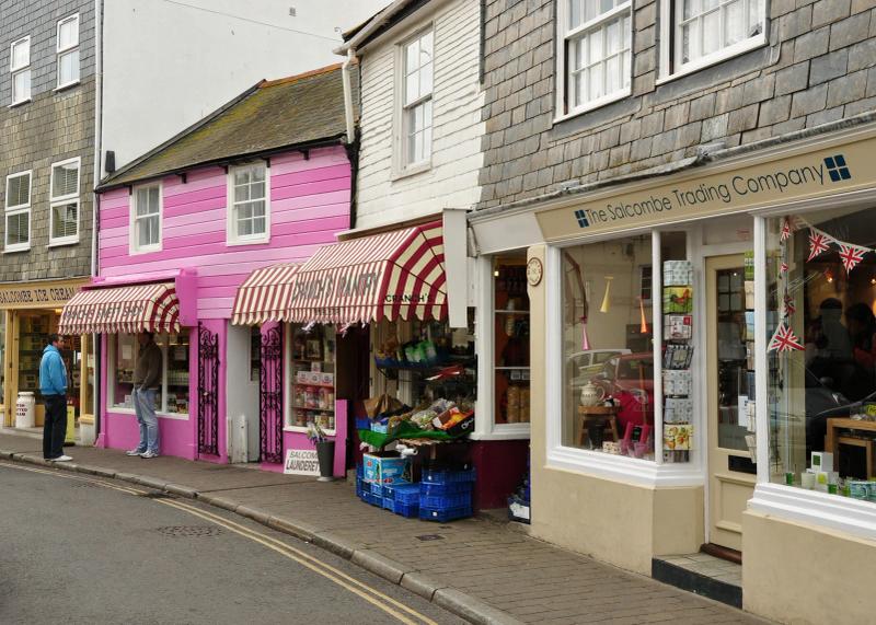 Shops along Fore Street in Salcombe, a narrow street of white and pastel-painted buildings with awnings and shopfronts on both sides